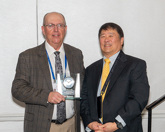 Drew DeGeorge, former JANNAF TEC Chair, receives a retirement gift from current JANNAF TEC Chair, Frank Tse, on behalf of the JANNAF TEC.